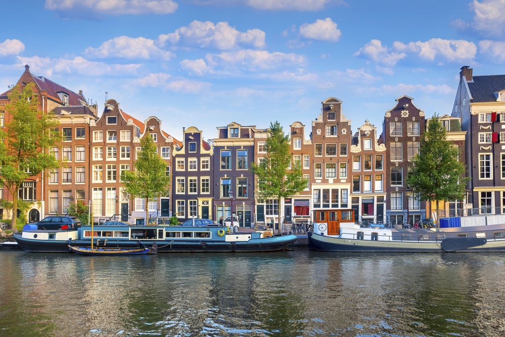 Amsterdam. Panoramablick auf das historische Stadtzentrum von Amsterdam. Traditionelle Häuser und Brücken von Amsterdam. Ein früher, ruhiger Morgen und die ruhige Reflexion der Häuser im Wasser. Europa