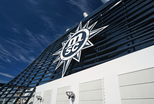Logo von MSC, das auf einem Kreuzfahrtschiff angebracht ist, vor klarem blauem Himmel.