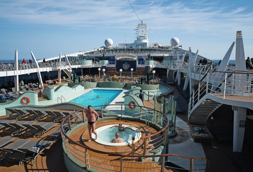 Deck eines Kreuzfahrtschiffs mit Pool und Sonnenliegen